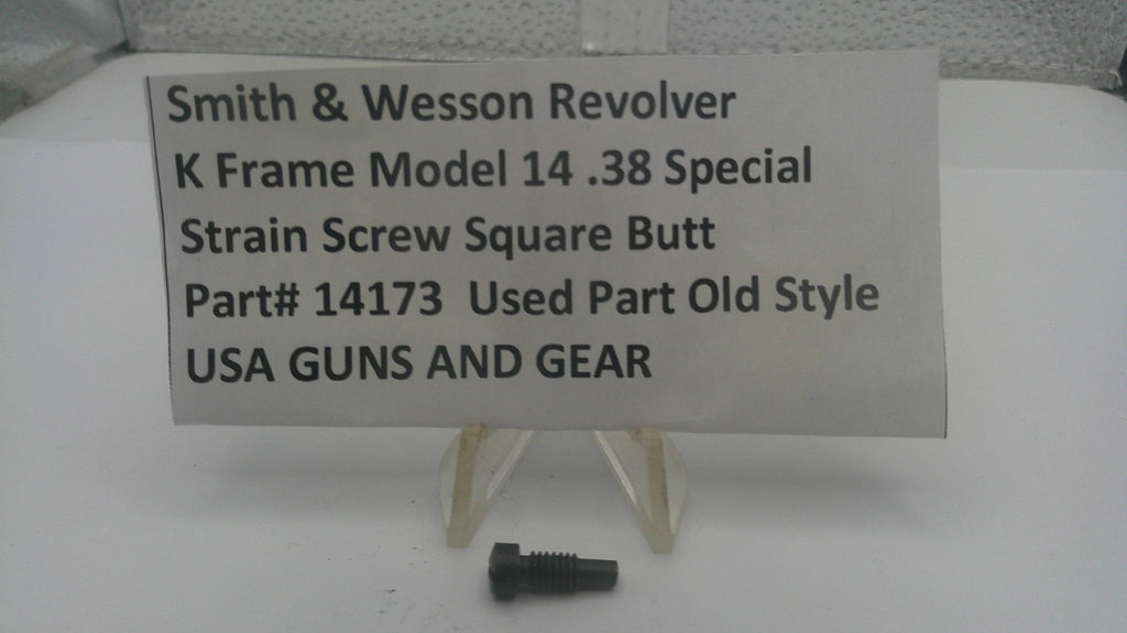 A small black metal strain screw part displayed below a white sign that reads 'Smith & Wesson Revolver K Frame Model 14 .38 Special Strain Screw Square Butt Part# 14173 Used Part Old Style USA GUNS AND GEAR' on a white surface.