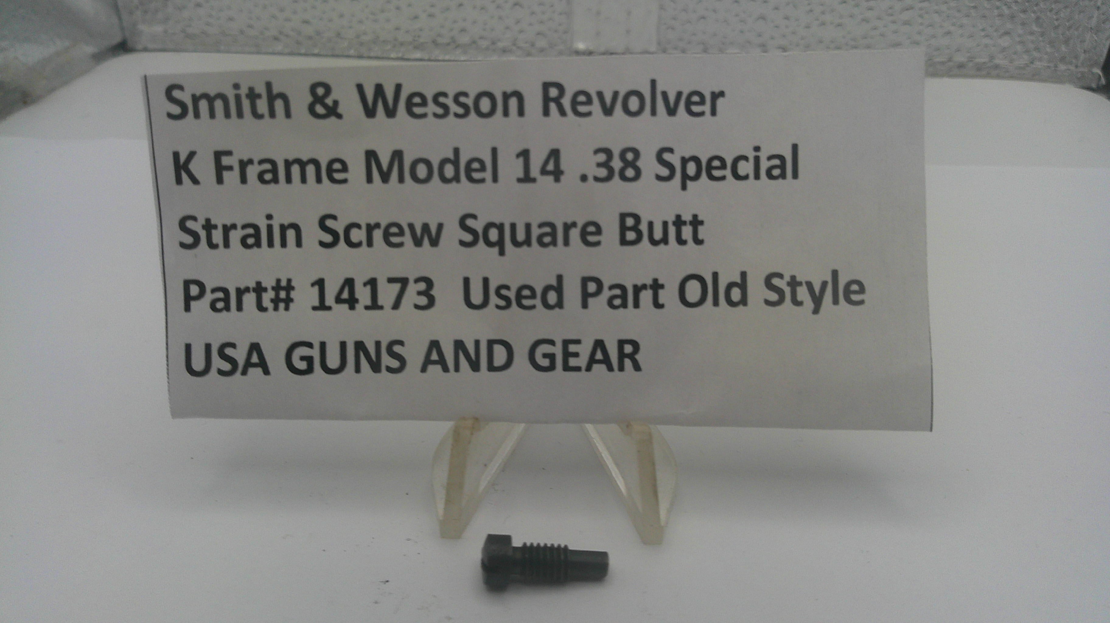 A small black metal strain screw part displayed below a white sign that reads 'Smith & Wesson Revolver K Frame Model 14 .38 Special Strain Screw Square Butt Part# 14173 Used Part Old Style USA GUNS AND GEAR' on a white surface.