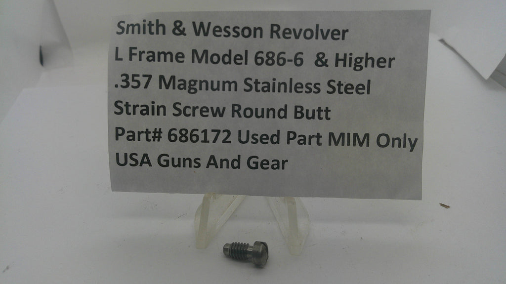 A small metal threaded screw part displayed on a clear plastic stand in front of a white sign that reads 'Smith & Wesson Revolver L Frame Model 686-6 & Higher .357 Magnum Stainless Steel Strain Screw Round Butt Part# 686172 Used Part MIM Only USA Guns And Gear'.