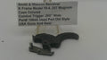 A used black metal Smith & Wesson revolver combat trigger part, displayed on a clear plastic stand in front of a white text label card.