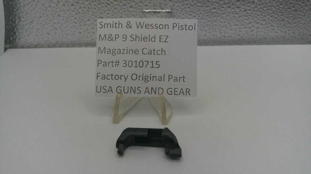 Smith & Wesson pistol magazine catch with a label on a white surface