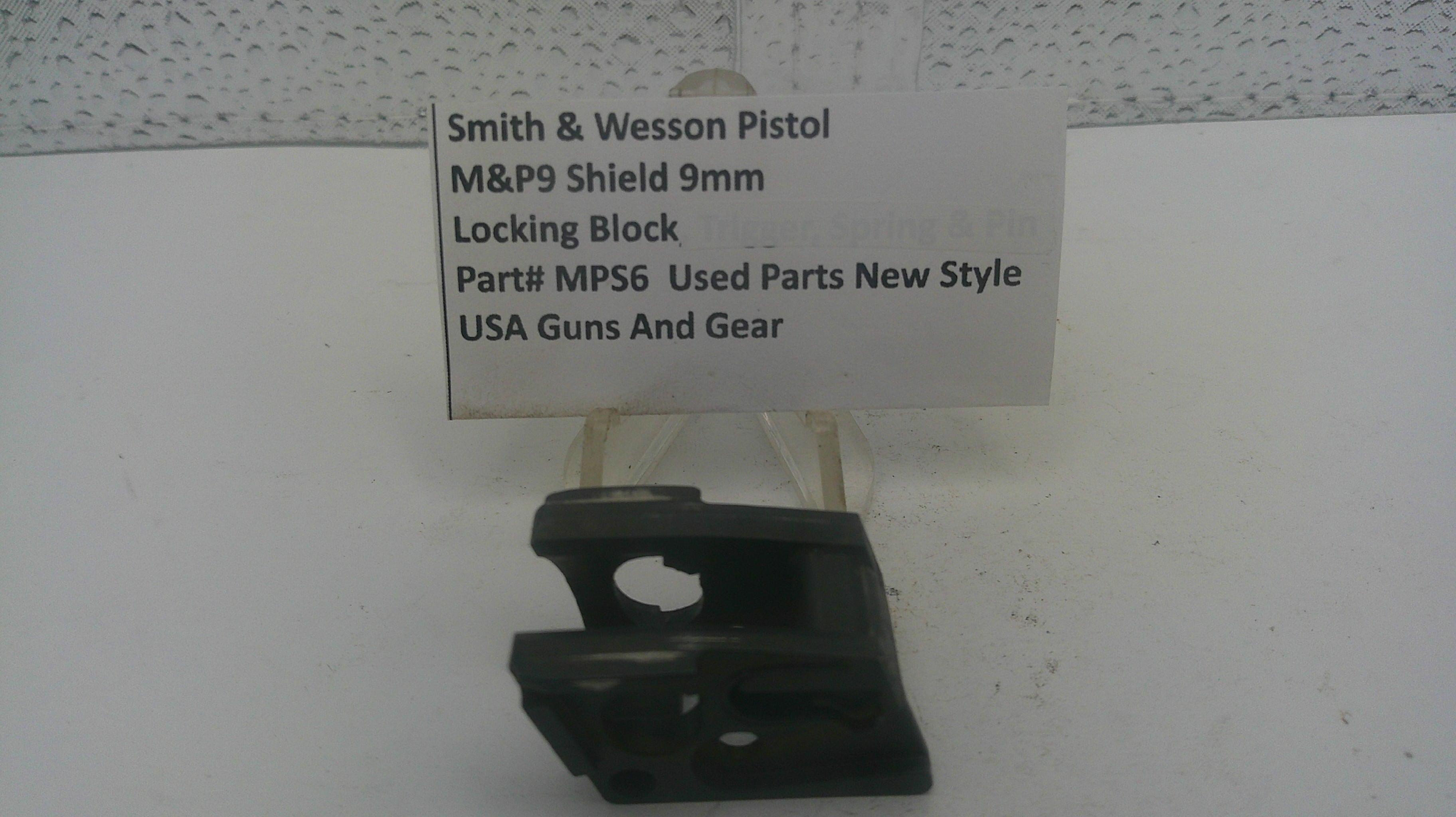 A black plastic Smith & Wesson pistol locking block part, displayed on a white surface with a white paper label card behind it.