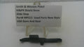 A small black metal slide stop part displayed on a clear plastic stand in front of a white label card that reads 'Smith & Wesson Pistol M&P9 Shield 9mm Slide Stop Part# MPS13 Used Parts New Style USA Guns And Gear'.