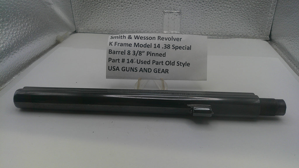 A black metal barrel component for a Smith & Wesson revolver, displayed horizontally in front of a white label card on a light gray textured background.