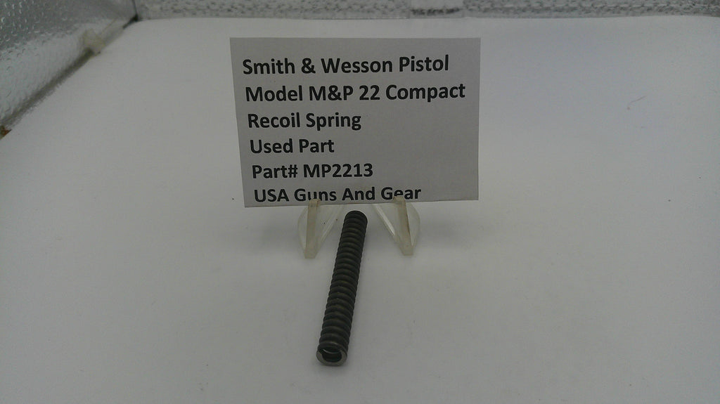 Smith & Wesson pistol recoil spring on a white surface with a label.
