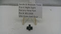 Smith & Wesson pistol front night sight on a white surface with a label.