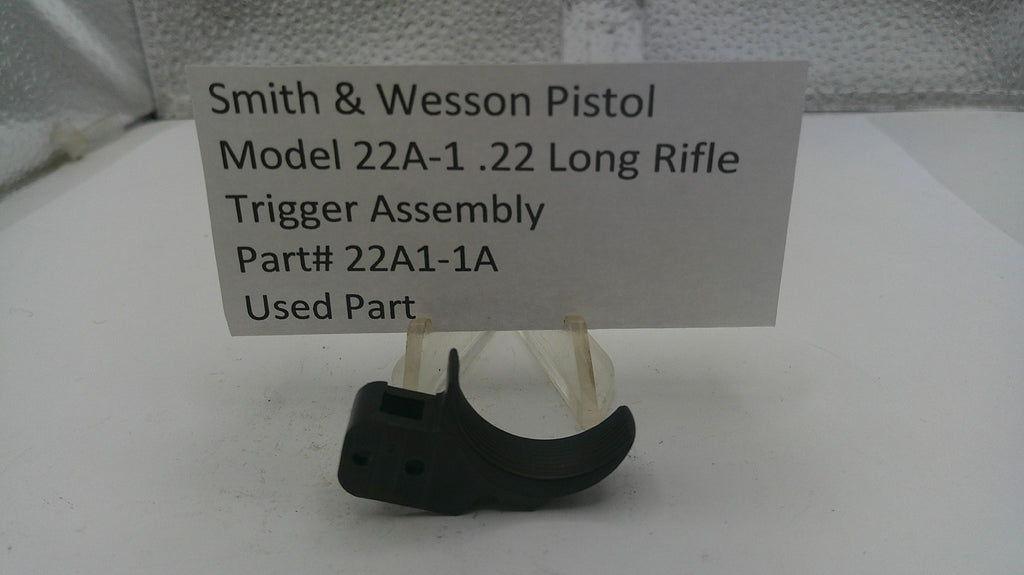 Smith & Wesson pistol trigger assembly on a stand with a label