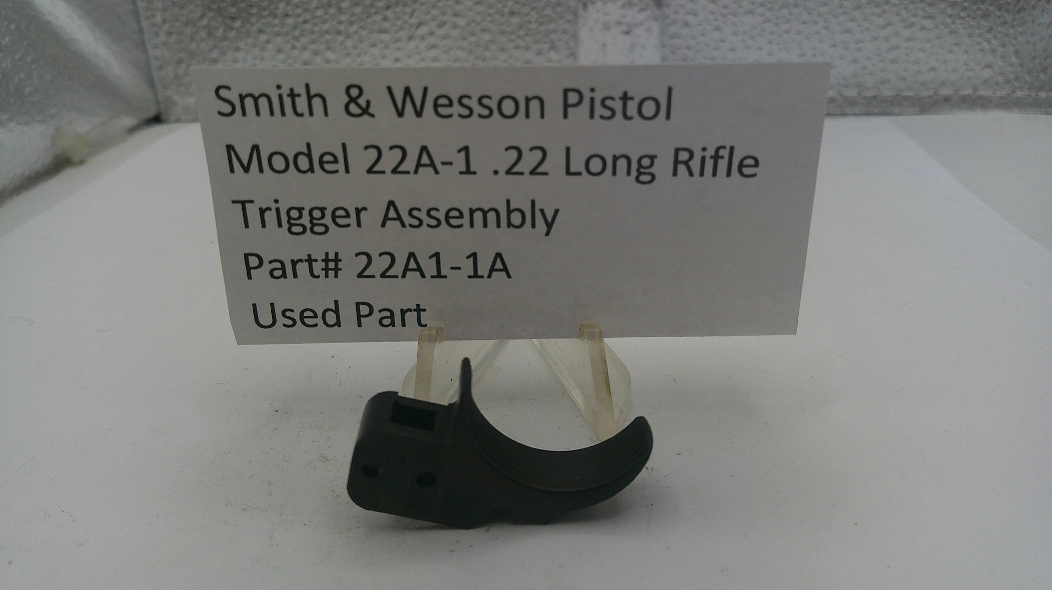 Smith & Wesson pistol trigger assembly on a stand with a label