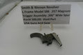 Smith & Wesson revolver trigger assembly on a white surface with a label.