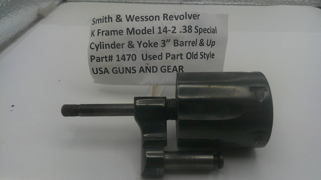 A used black metal revolver cylinder and yoke part, labeled with part number 1470, shown on a white surface with a paper tag reading 'Smith & Wesson Revolver K Frame Model 14-2 .38 Special Cylinder & Yoke Barrel & Up'.