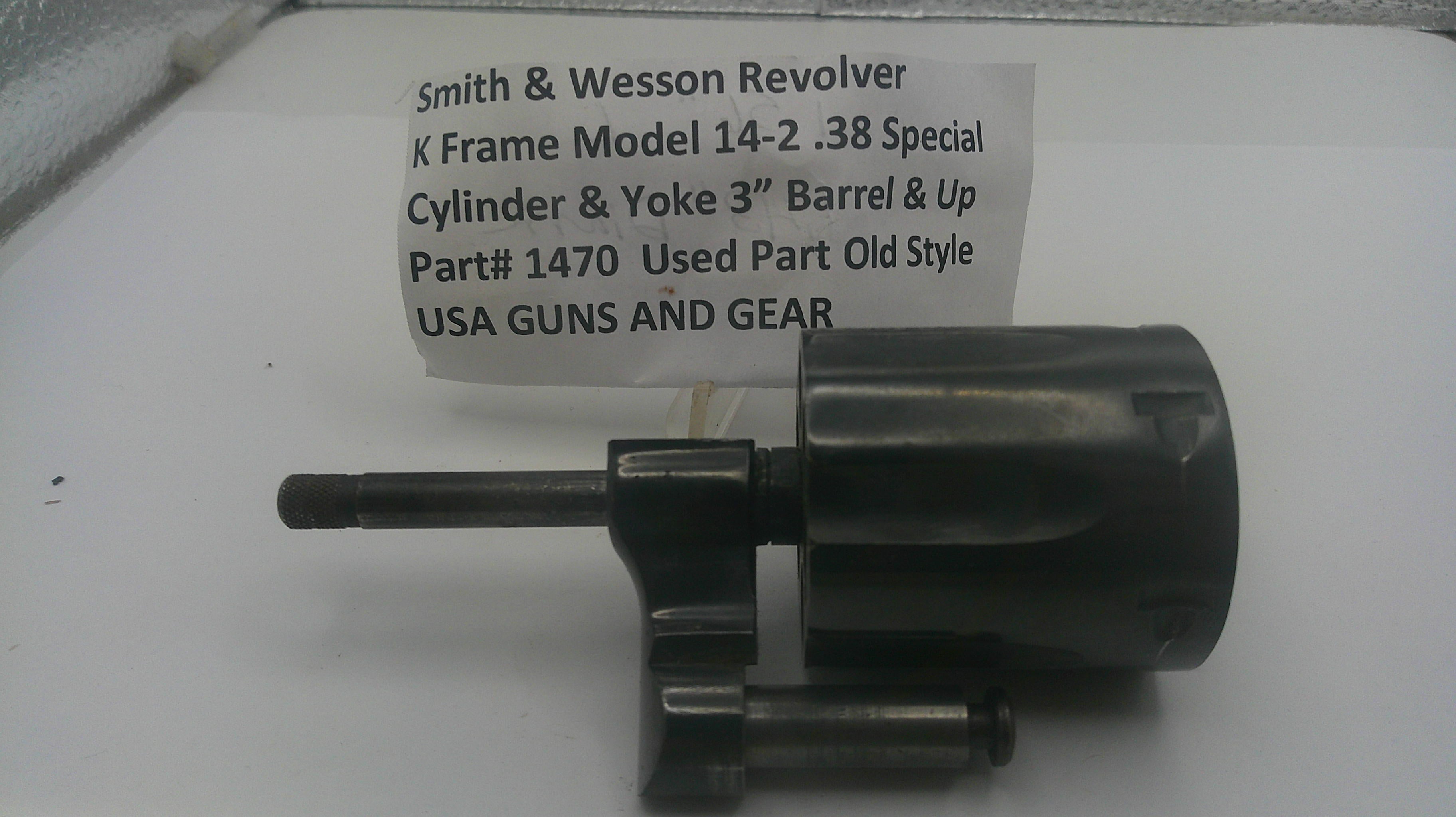 A used black metal revolver cylinder and yoke part, labeled with part number 1470, shown on a white surface with a paper tag reading 'Smith & Wesson Revolver K Frame Model 14-2 .38 Special Cylinder & Yoke Barrel & Up'.