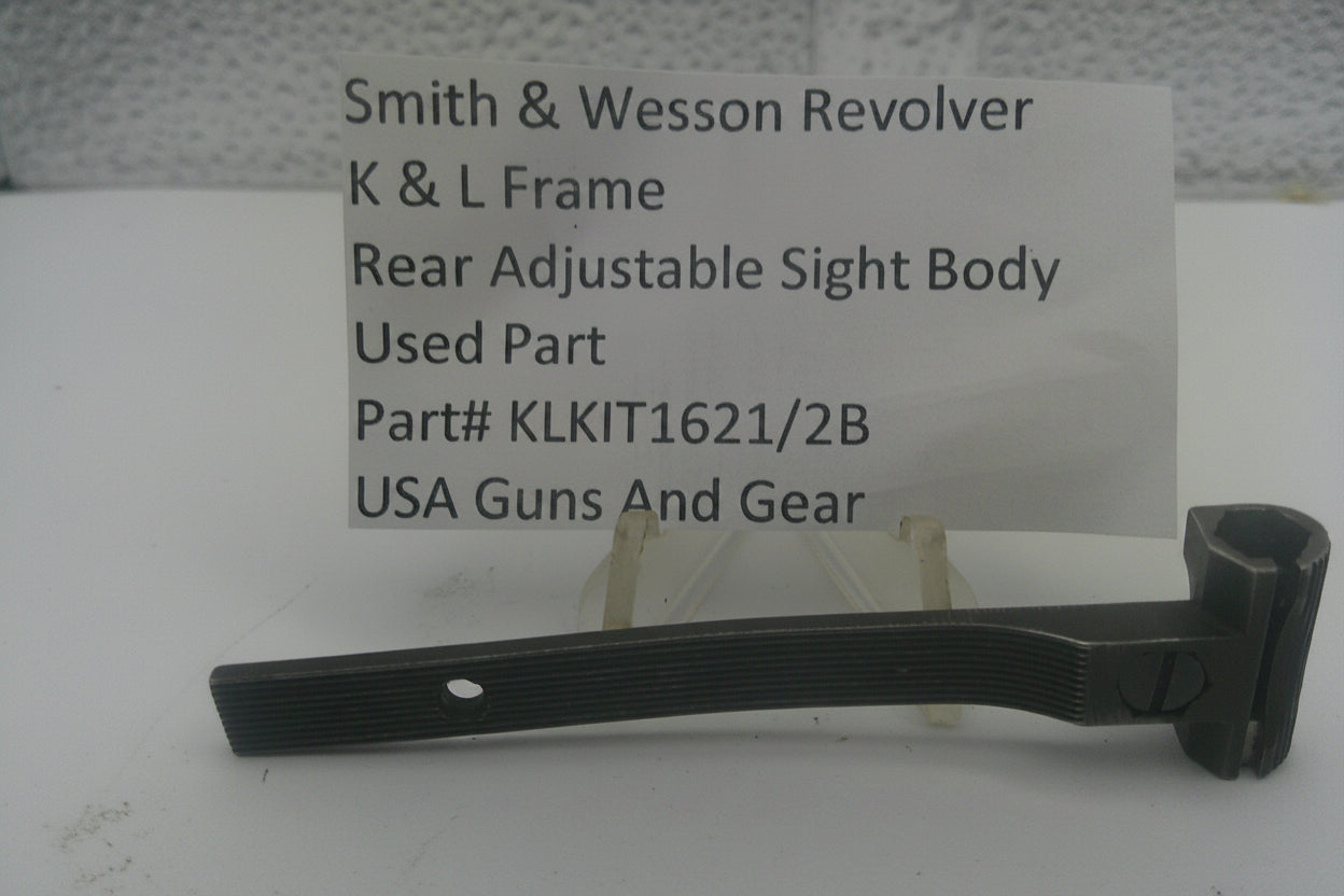A used black metal sight body part for a Smith & Wesson revolver, displayed on a small stand in front of a white card with product details.