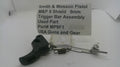 A used Smith & Wesson M&P 9 pistol trigger bar assembly, part number MP9F1, displayed on a white surface with a paper label card behind it.