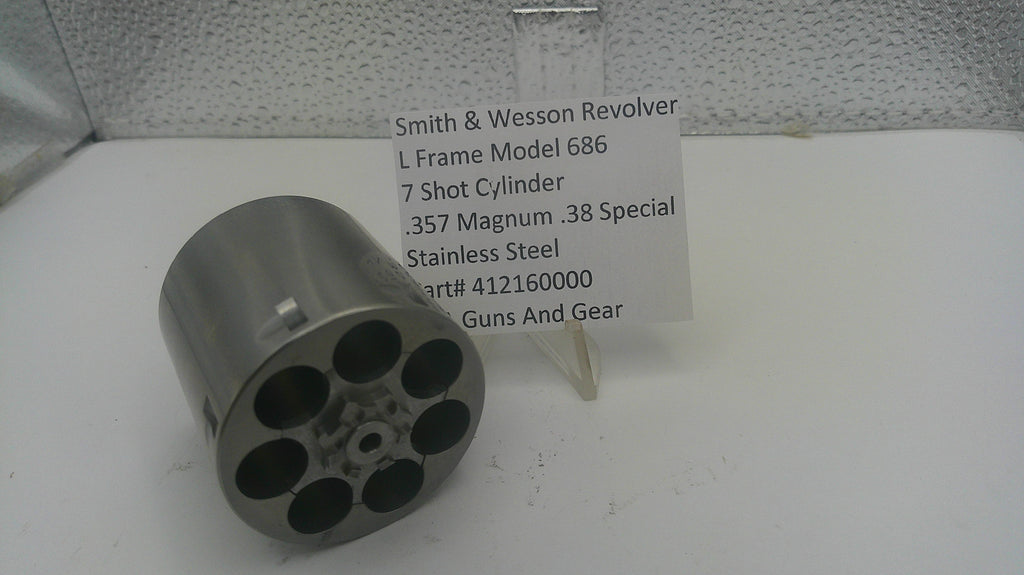 A stainless steel 7-cylinder revolver cylinder holder, shown next to a white label card identifying it as a Smith & Wesson revolver part.