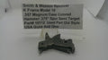 A used metal firearm part, identified as a Smith & Wesson revolver hammer, displayed on a white surface with a text label card in the background.