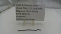Smith & Wesson pistol magazine catch spring with a label on a white background
