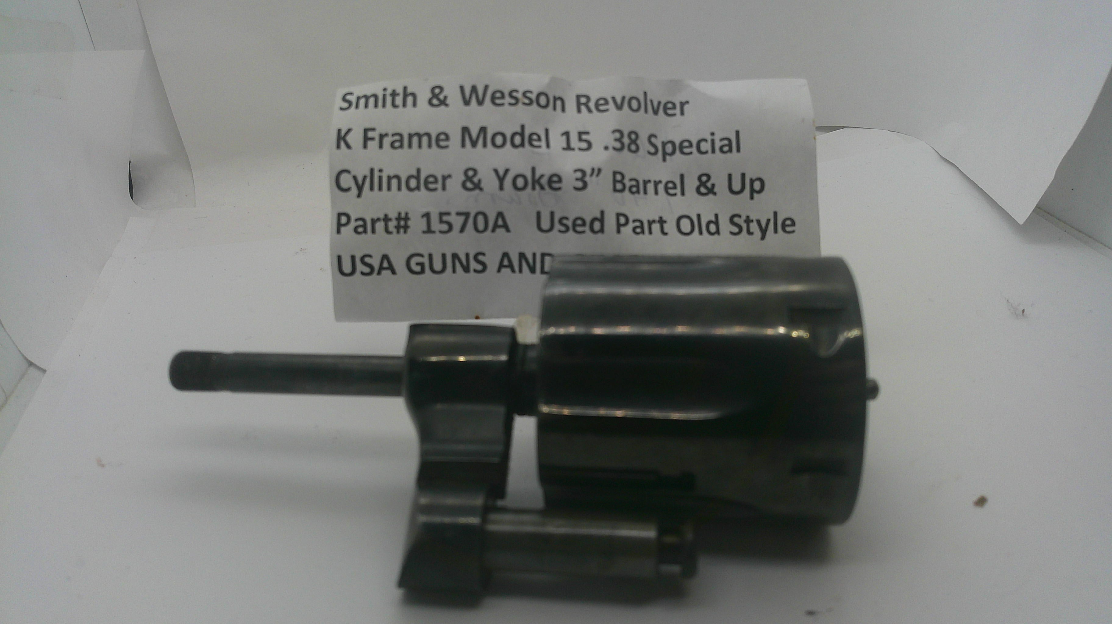 A used black metal Smith & Wesson revolver cylinder and yoke part, shown on a white background with a handwritten paper label behind it.