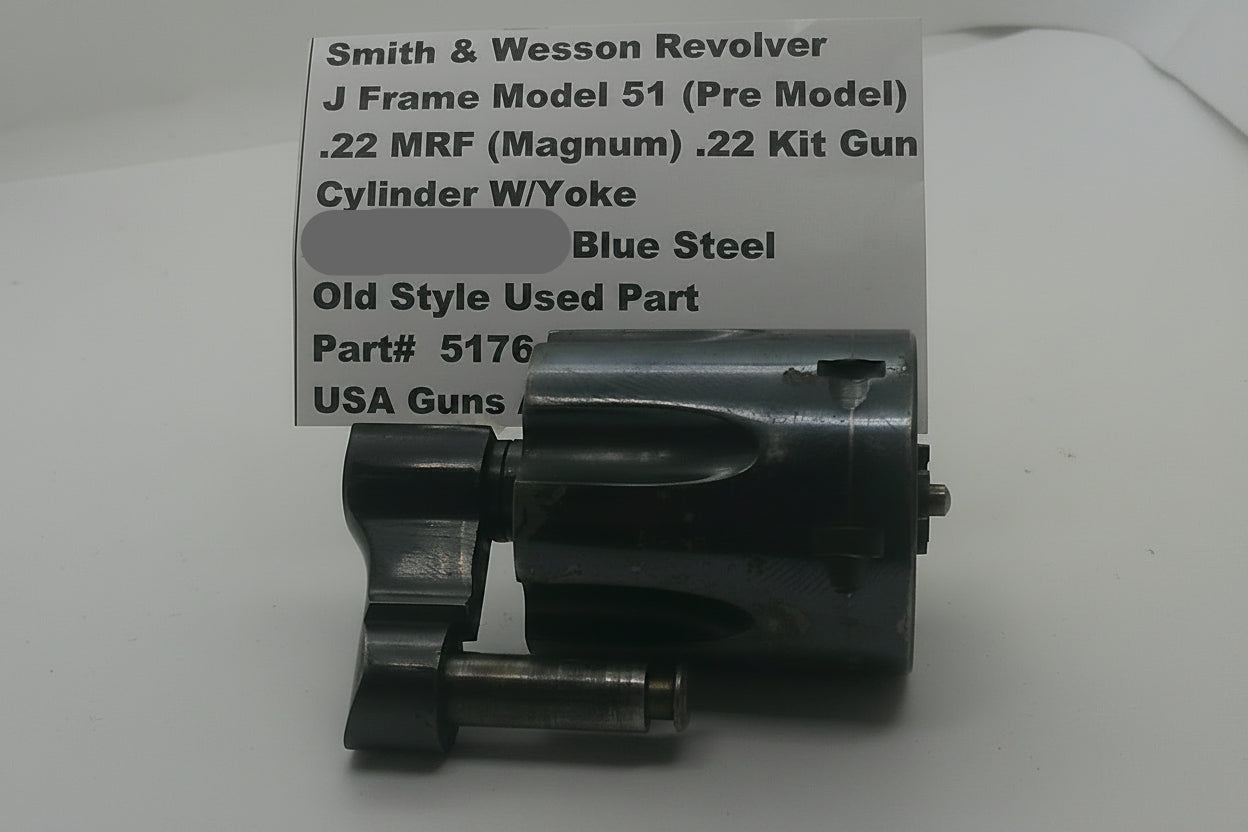 A used metal Smith & Wesson revolver cylinder and w/ye assembly, shown next to a handwritten paper label with part details.
