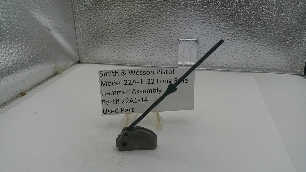 Smith & Wesson pistol hammer assembly on a white surface with a label.
