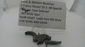 A used Smith & Wesson revolver trigger component on a clear plastic stand in front of a paper label card with product details.