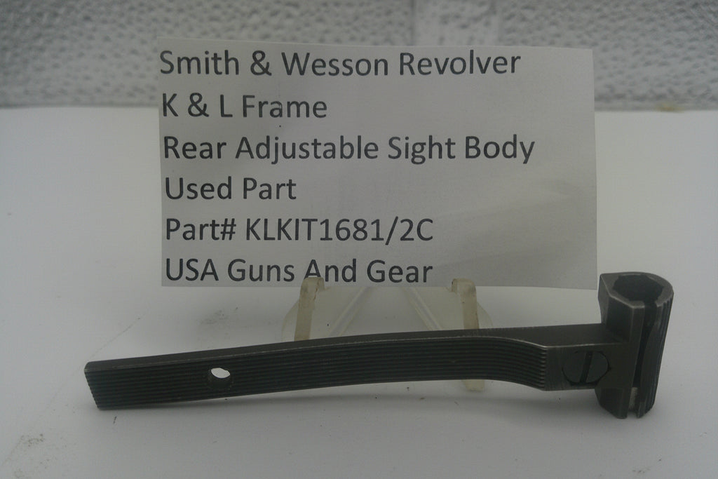 A used black metal sight body part for a Smith & Wesson revolver, displayed on a small stand in front of a white card with product details.