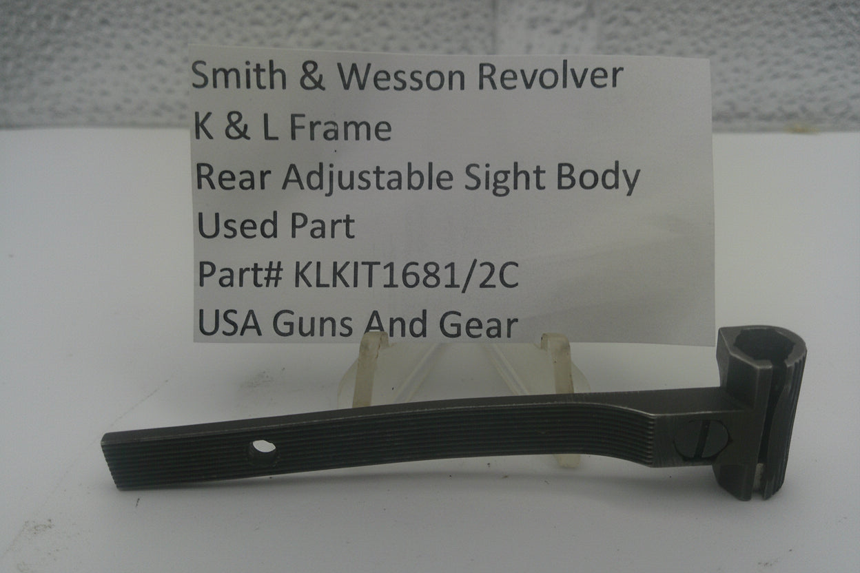 A used black metal sight body part for a Smith & Wesson revolver, displayed on a small stand in front of a white card with product details.