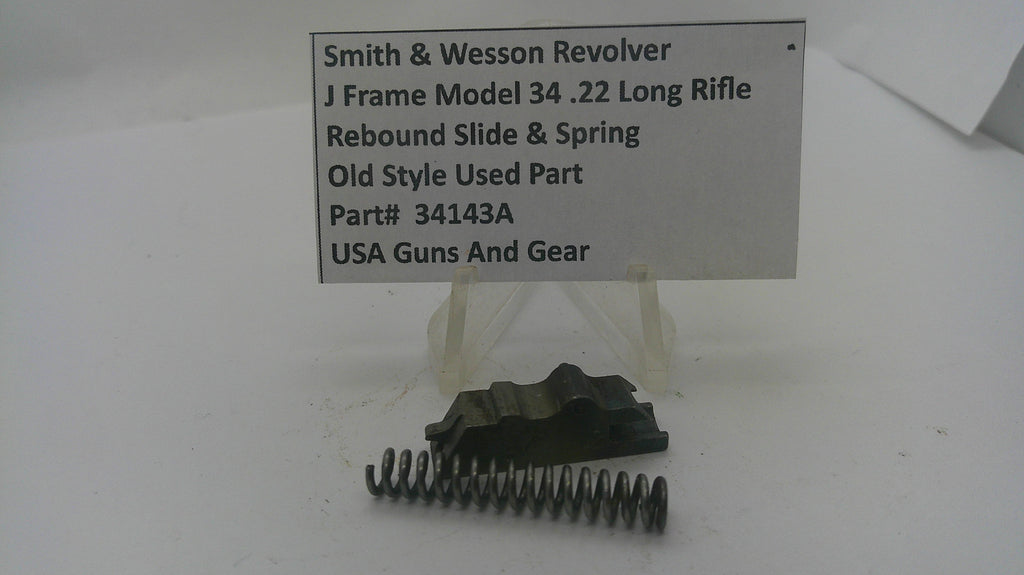 A used metal recoil spring and black slide assembly for a Smith & Wesson revolver, displayed on a clear plastic stand beneath a white label card with product details.