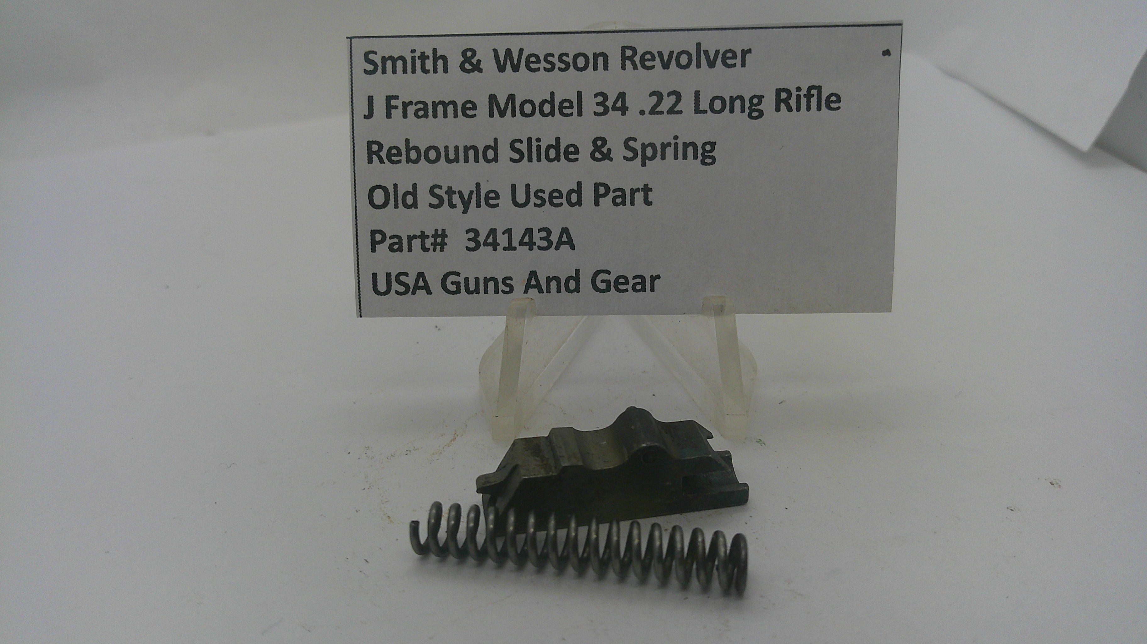 A used metal recoil spring and black slide assembly for a Smith & Wesson revolver, displayed on a clear plastic stand beneath a white label card with product details.