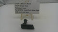 A small black plastic takedown lever part displayed on a white surface in front of a small clear stand with a label card reading 'Smith & Wesson Pistol M&P9 Shield 9mm Takedown Lever Part# MPS9 Used Parts New Style USA Guns And Gear'.
