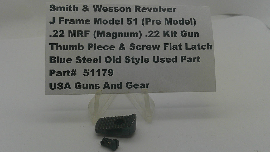 A small black metal revolver grip or thumb piece part displayed on a clear stand, with a white label card behind it reading 'Smith & Wesson Revolver J Frame Model 51 (Pre Model) .22 MRF (Magnum) .