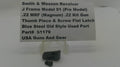 A small black metal revolver grip or thumb piece part displayed on a clear stand, with a white label card behind it reading 'Smith & Wesson Revolver J Frame Model 51 (Pre Model) .22 MRF (Magnum) .