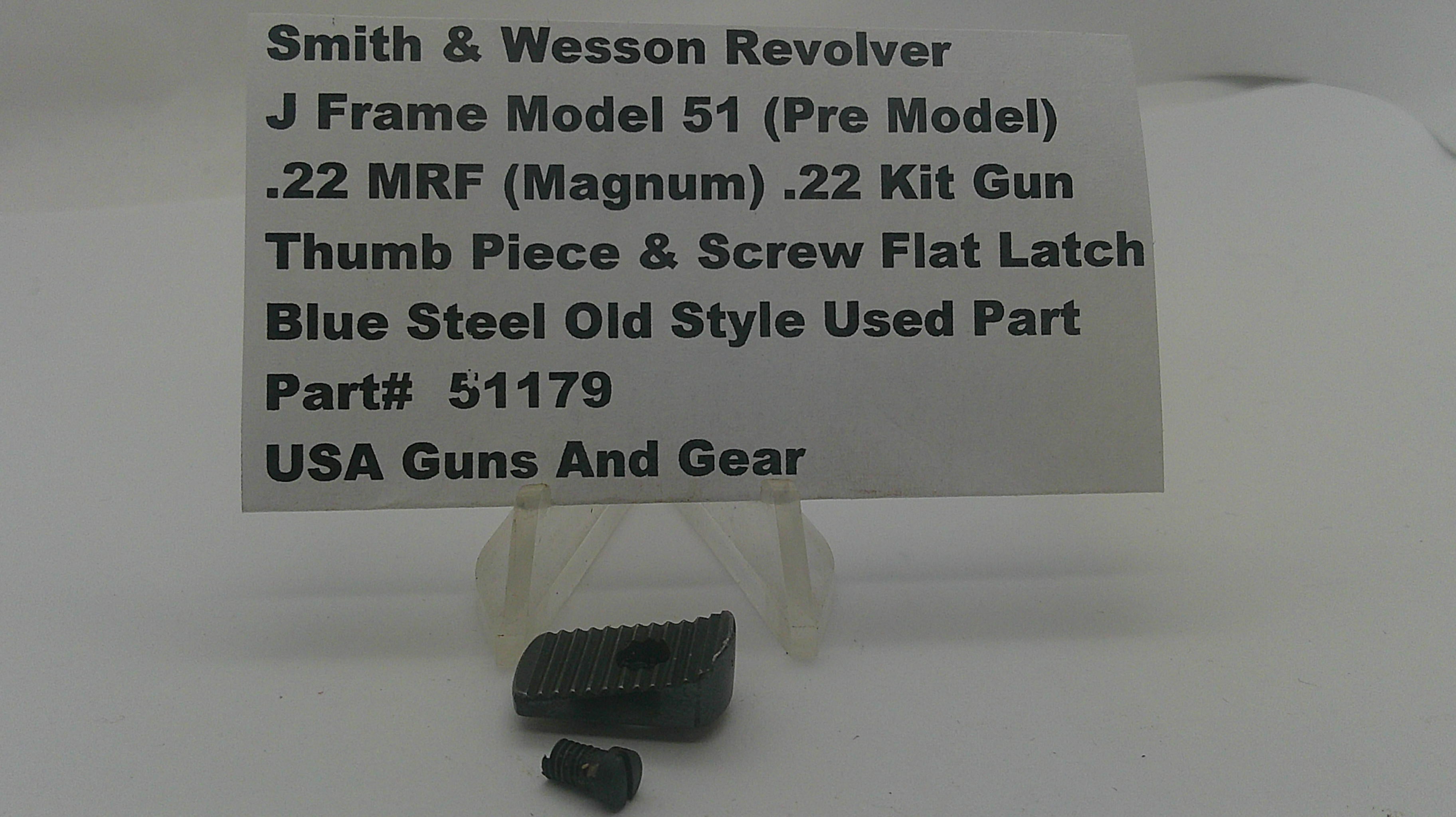 A small black metal revolver grip or thumb piece part displayed on a clear stand, with a white label card behind it reading 'Smith & Wesson Revolver J Frame Model 51 (Pre Model) .22 MRF (Magnum) .