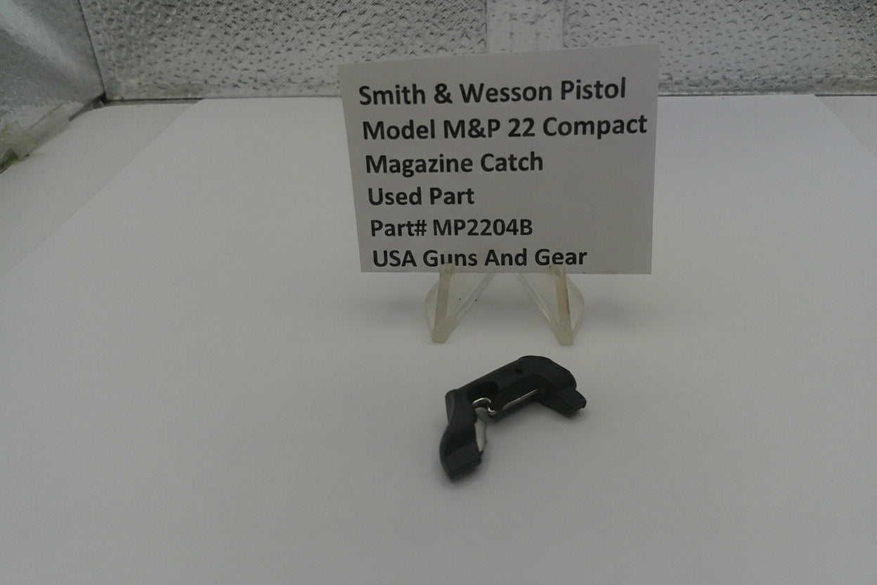 Smith & Wesson pistol magazine catch on a white surface with a label
