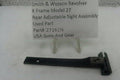 A used black metal rear adjustable sight assembly for a Smith & Wesson revolver, displayed on a white surface with a white paper label card on small plastic stands.