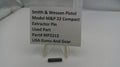 Smith & Wesson pistol part with a label on a white surface