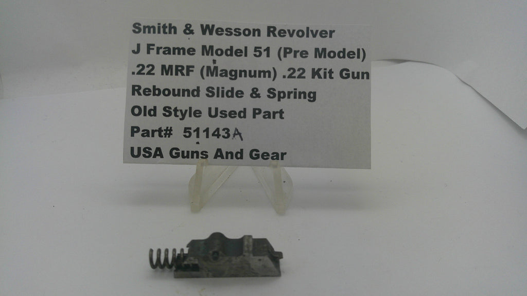 A used metal revolver slide and spring part displayed on a small clear stand, with a paper label card behind it reading 'Smith & Wesson Revolver J Frame Model 51 (Pre Model) .22 MRF (Magnum) .