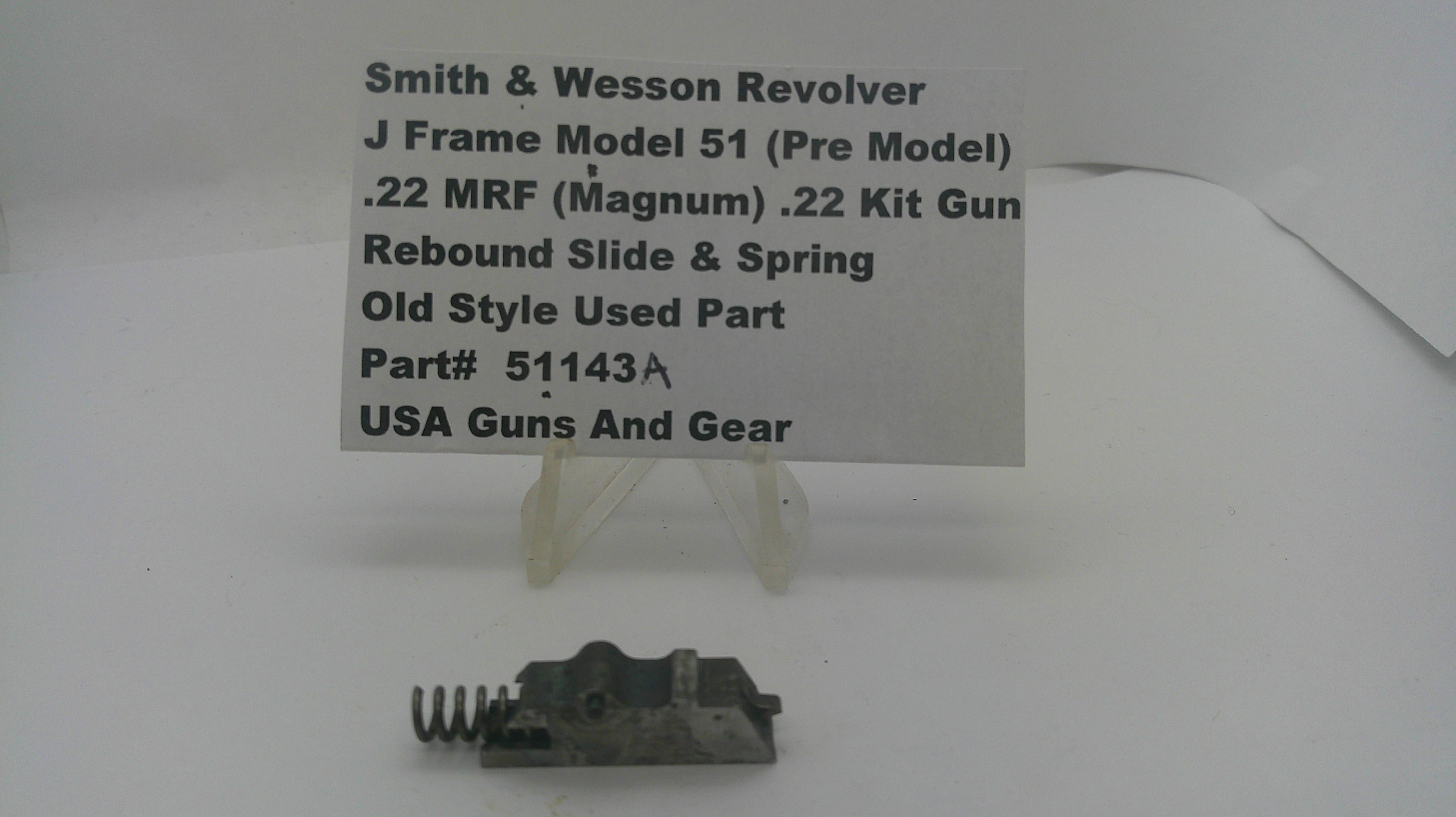 A used metal revolver slide and spring part displayed on a small clear stand, with a paper label card behind it reading 'Smith & Wesson Revolver J Frame Model 51 (Pre Model) .22 MRF (Magnum) .