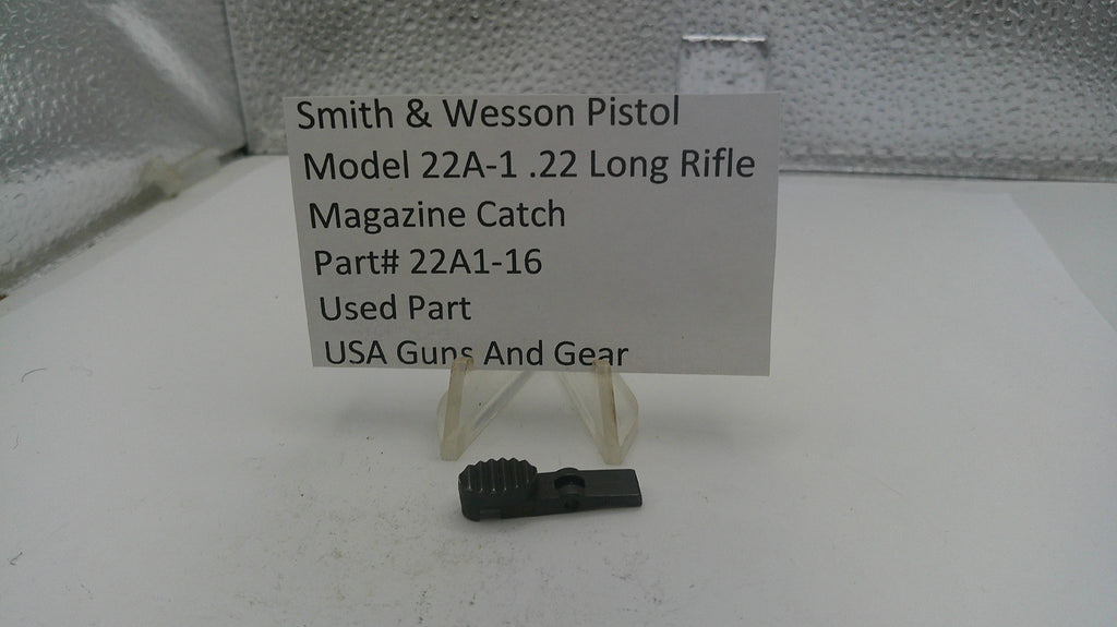 Smith & Wesson pistol magazine catch part with label on a white surface