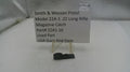 Smith & Wesson pistol magazine catch part with label on a white surface