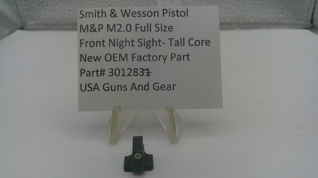 A small black metal firearm accessory part displayed on a clear plastic stand in front of a white sign that reads 'Smith & Wesson Pistol M&P M2.0 Full Size Front Night Sight-Tall Core New OEM Factory Part Part# 301283 USA Guns And Gear'.