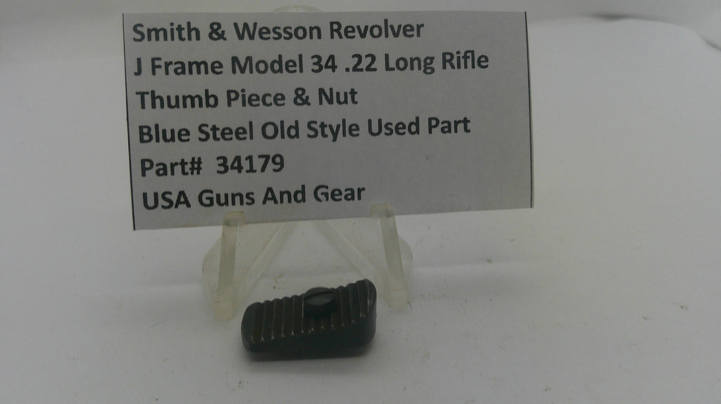 A small dark metal gun part displayed on a clear plastic stand in front of a printed label card. The label reads: Smith & Wesson Revolver, J Frame Model 34 .