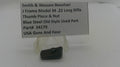A small dark metal gun part displayed on a clear plastic stand in front of a printed label card. The label reads: Smith & Wesson Revolver, J Frame Model 34 .