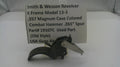 A used black metal Smith & Wesson revolver combat hammer part, displayed in front of a white paper label card with product details.