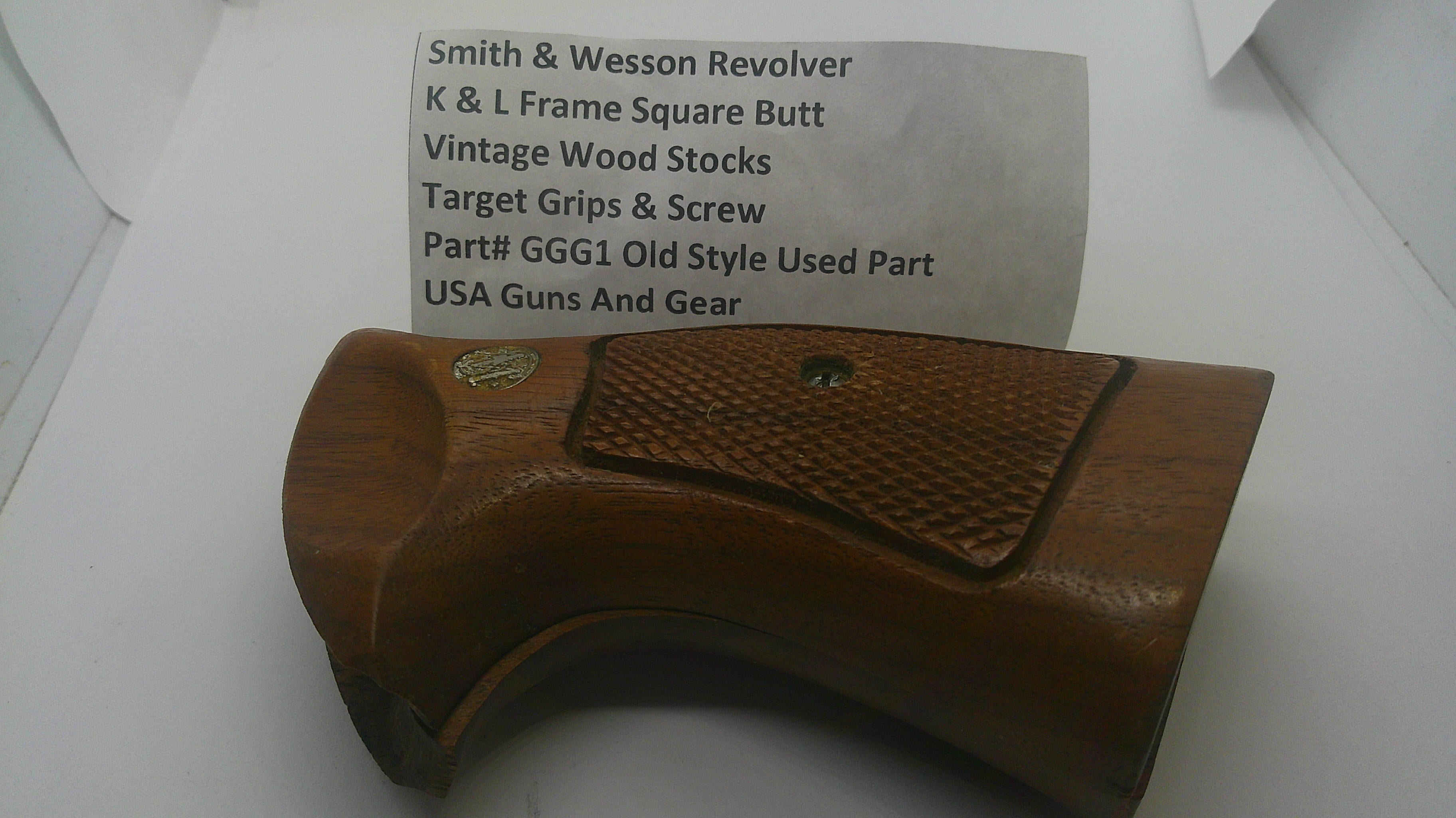 A used wooden revolver grip replacement part, made of brown wood with a textured checkered grip panel and a small brass screw, shown next to a paper label identifying it as a Smith & Wesson revolver part.