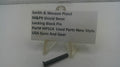 A small black metal locking block pin displayed on a clear plastic stand next to a white label card that reads 'Smith & Wesson Pistol M&P9 Shield 9mm Locking Block Pin Part# MPS14 Used Parts New Style USA Guns And Gear' on a white surface.