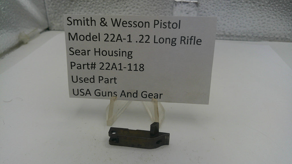 Smith & Wesson pistol sear housing on a stand with a label