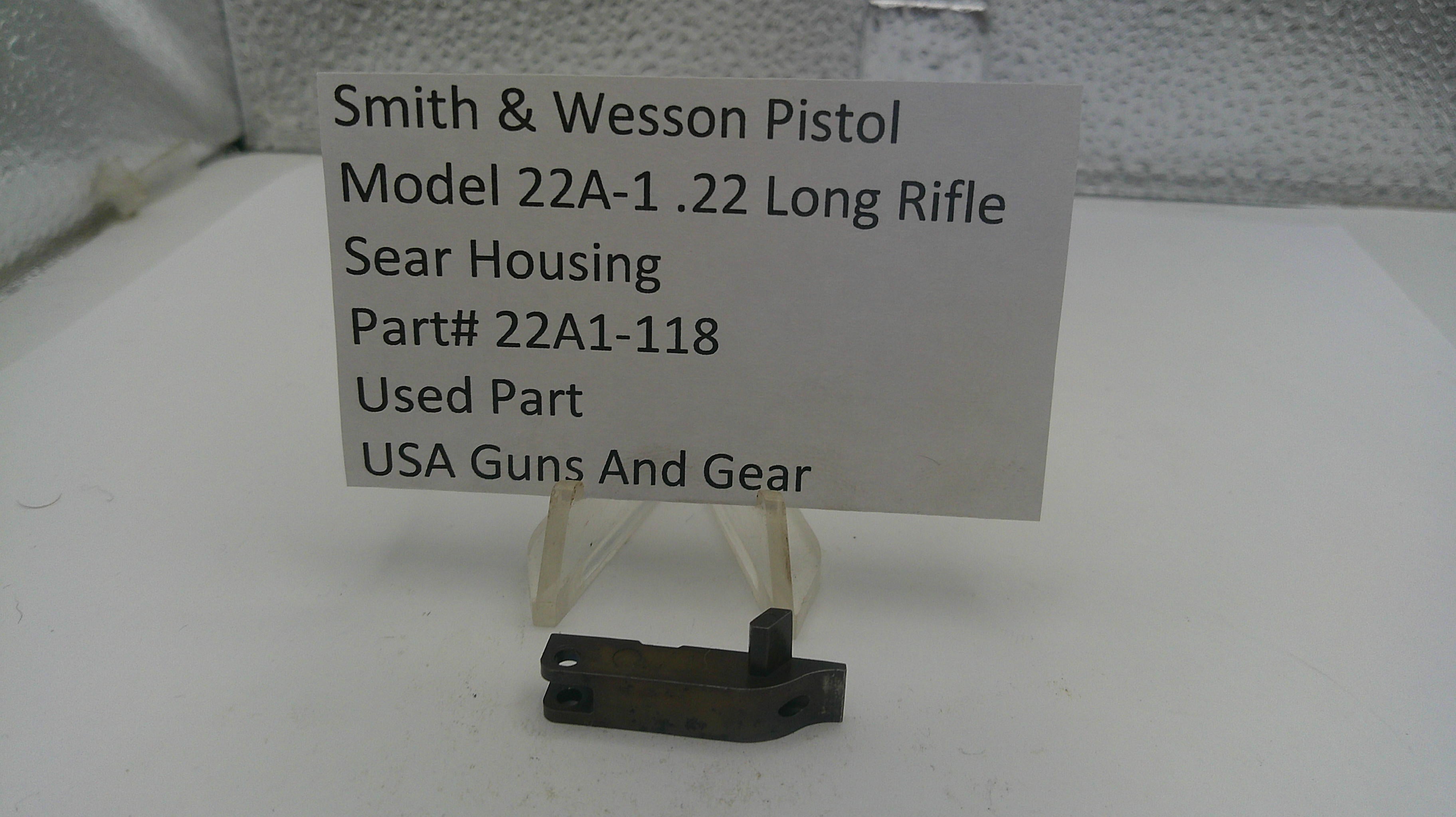 Smith & Wesson pistol sear housing on a stand with a label