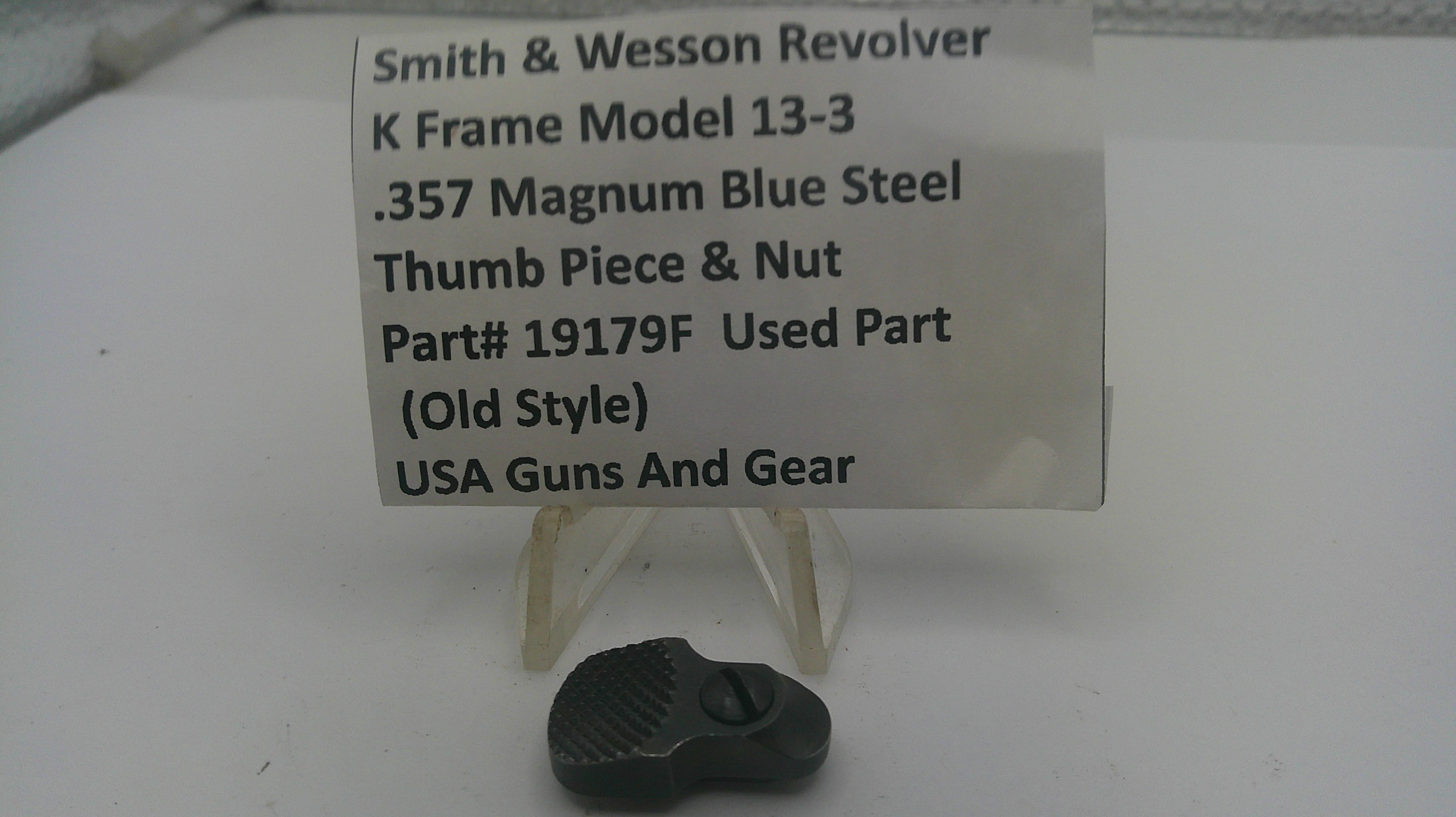 A small black metal thumb piece and nut part for a Smith & Wesson revolver, displayed below a white label card on a white surface.