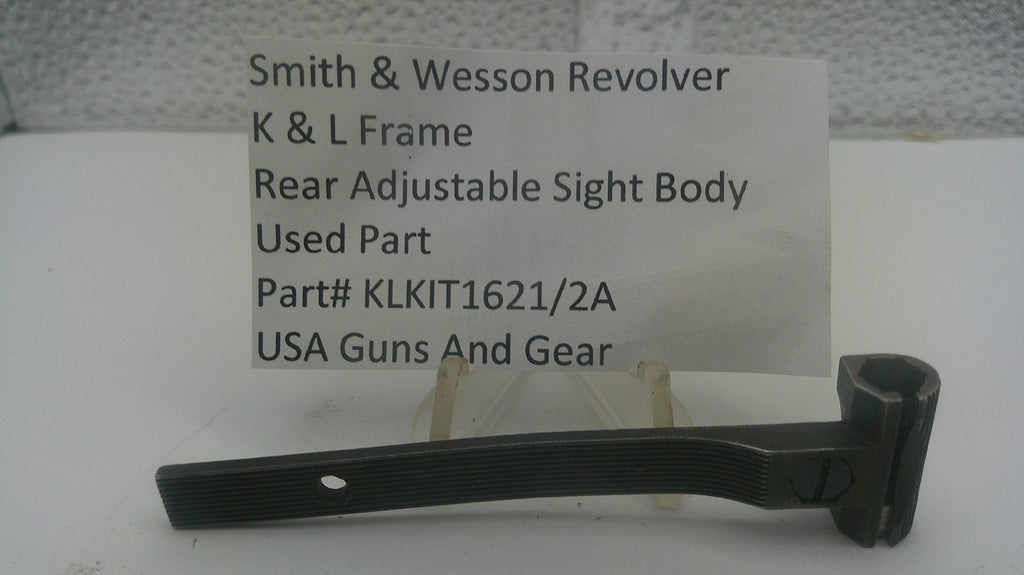 A used black metal sight body part for a Smith & Wesson revolver, displayed on a small stand in front of a white card with product details.
