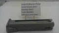 A dark gray metal receiver or grip component for a Smith & Wesson pistol, displayed on a white surface with a paper label card behind it reading 'Smith & Wesson Pistol SW22 Victory Bolt Stainless Steel Part# 3002663 USA Guns And Gear'.
